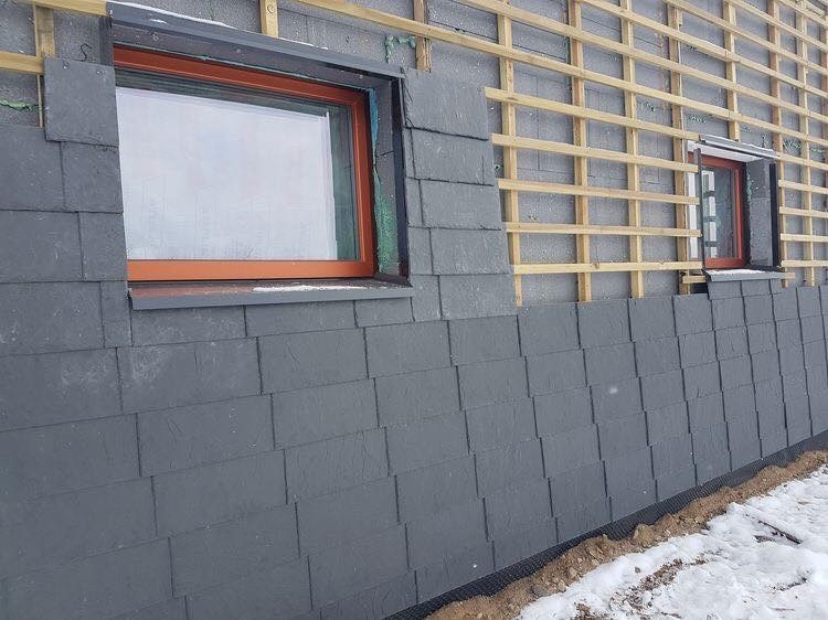 Installation of natural slate on the walls of the house